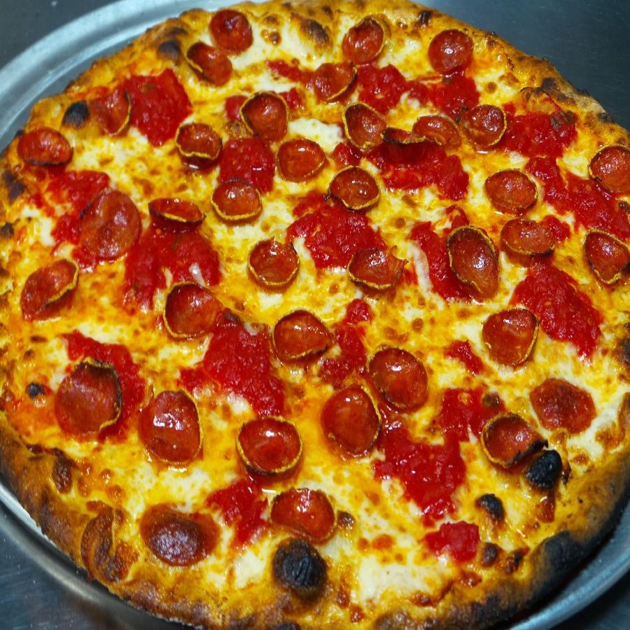A pepperoni pizza on a metal plate.